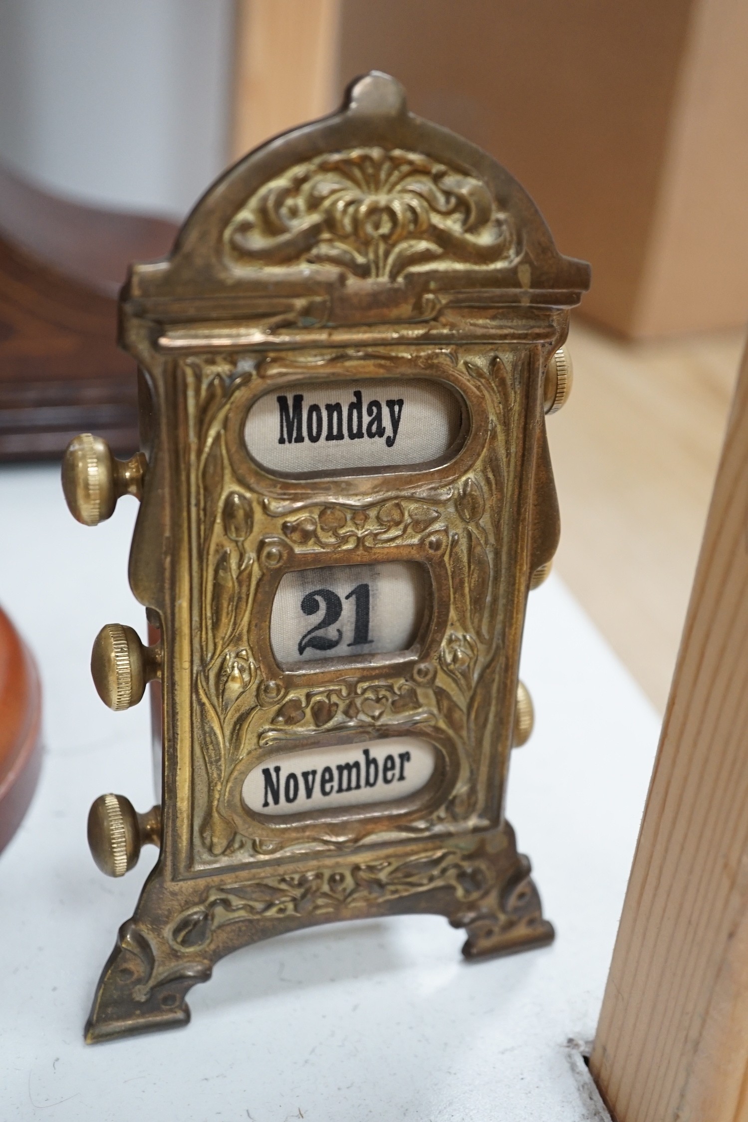 An early 20th century inlaid mahogany mantel clock, a skeleton clock under glass dome, a brass desk calendar and a 19th century French framed print, skeleton clock and dome 32cms high